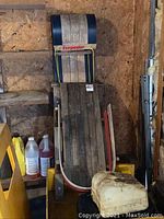 Wooden Torpedo toboggan leaning against wall with visible wear and blue end caps.