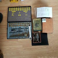 Full view of the metal case with taps, dies, ratchet wrench, accessories, boxed extra taps, and the vintage Machinery's Handbook.