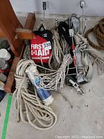 Photo showing multiple coiled ropes, first aid kit, and hooks from an over-the-door storage rack