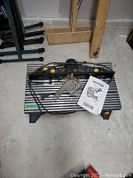 Top-down view of router table assembly showing aluminum table top, fence, motor housing, power cord, dust guard and manual