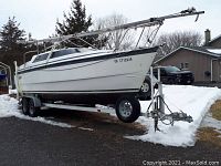 Boat hull and mast on tandem axle trailer parked outdoors
