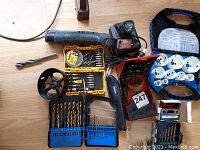 Full overview of all tools and bits showing cordless cutter, drill bits, cordless drill with battery and charger, hole saws, and driver bits set.