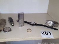 Group view of two strapped watches, loose watch case, Givenchy lighter, gold ring and pocket knife