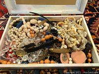 Full box showing assorted bead necklaces, clear beads, and watches.