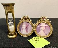 French mini double photo frame with two vintage style portrait paintings and a decorative hourglass clock with brass finish and white sand.