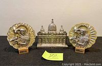 Front view of all three items on black cloth including the basilica model and two saint relief plaques on either side