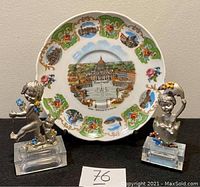 Photo showing two detailed vintage Italian pewter figurines and a decorative Bavaria plate with Rome landmarks as the background