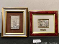 Both framed silver plaques side by side