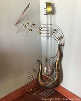 Photo showing full view of the stylized metal guitar wall art with musical note accents against a wall corner.