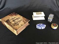 Overview of all 5 boxes: a book-shaped large box with nautical design, three porcelain boxes of various shapes and one small round box with compass design lid.