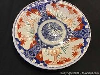 Top view showing intricate hand painted patterns in red, blue, cream, and green enamel, with bird and floral motifs on scalloped edge plate.
