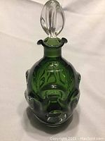 Front view of green art glass decanter showing applied clear glass details and thick green glass body