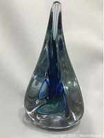 Clear teardrop-shaped art glass paperweight showing internal blue-green swirl