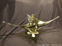 Front left angle view of elongated olive green glass bowl with flowing edges on dark background.