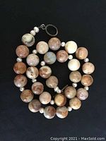 Coiled jasper and pearl necklace on black background showing bead texture and clasp.