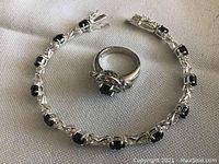 Sterling silver bracelet and ring laid on a fabric surface showing the design and gemstones clearly.