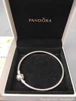 Pandora silver charm bracelet with single ball charm inside a black velvet-lined box with Pandora logo