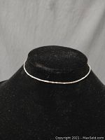 Front view of the small thin gold chain displayed on a black mannequin bust showing its delicate size and style.