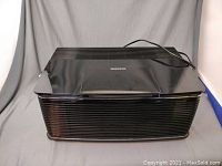 Front side view of black Oreck air purifier with vented design and power cord.