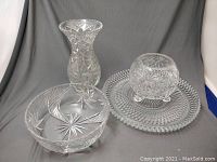 Front view of all four cut crystal items showing the vase, decorative bowl, platter, and footed bowl.