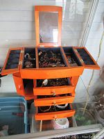 Open jewelry box with mirror, top compartments and drawers visible, contents inside