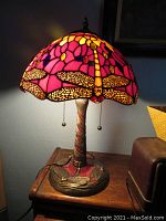 Lit lamp showing full stained glass shade and metal base