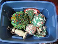 Lot of four vintage ceramic Christmas trees with multi-colored bulbs in a blue tote, including a light-up tree with switch.
