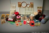 Photo showing the entire assortment of yarns, buttons, bobbins, needles, pins, rulers, plastic spool holders, and small crafting tools arranged on a white surface.