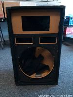 Front view of empty Pyle Pro PASC-15 speaker cabinet showing large round opening for 15-inch speaker and two rectangular openings for horn tweeters above it. Cloth covering shows wear and separation.
