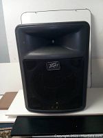 Front view of black Peavey speaker outer shell, metal grille intact. Speaker drivers and control panel removed.