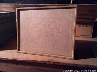 Front view showing rectangular wooden framed speaker with beige fabric grill covering the speaker driver.