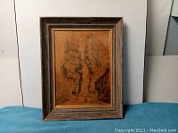 Photo showing the front of the framed painting with visible brown toned landscape art and wooden frame with gilded inner frame.