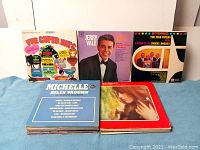 Covers of several vintage LP records including The Super Hits compilation, Jerry Vale album, and The Pied Pipers tribute album, arranged upright showing artwork and titles.