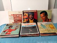 Front overview of the stack of vintage LP vinyl records showing covers of albums by Luciano Pavarotti, Harry Belafonte, Leonard Bernstein, and others.