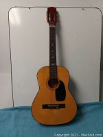 Full front view of Castilla junior size acoustic guitar showing natural wood body, black pickguard, and bowed neck.