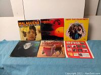 Front view of a selection of 6 LP records from the lot including Malaguena by Percy Faith, Sunset and Evening Star, Happy Time Polka Party, music man cast recording, Songs for the Next Crowd, and The Pep Seco Singers