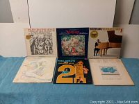 Photo showing six LP vinyl records laid out on a blue towel, including Elvis Greatest Hits, Wurlitzer, Roger Williams, Paul Anka's Golden Hits, Johnny Mathis, and a female vocalist album.