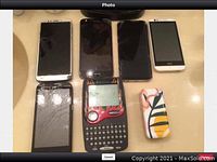 Overview of multiple cell phones showing cracked and intact screens, plus two colorful phone cases and one vintage-style QWERTY phone.