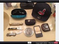 Overview of men's lot items including hat, sunglasses in case, knives, watch in brown pouch, small tin, magnifier, and black pouch with keychain