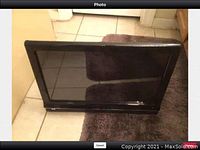 Front view of HP 600 TouchSmart all-in-one computer with touchscreen display, turned off, on a tile floor with brown rug.