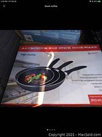 Box displaying three non-stick frying pans with food inside one pan. Shows set size and pan handles.