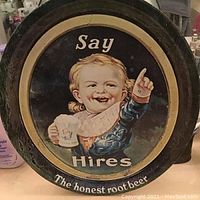 Close-up image of the front of the vintage Hires root beer advertising tin showing the smiling child holding a frosted mug with 'Say Hires The honest root beer' text.