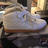 Side view of white Fila high-top sneaker showing gum sole and ankle strap