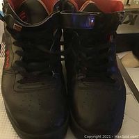 Front view of black Fila sneakers showing laces, perforated toe area, and logo on tongue