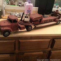 Side view of rusty red tin fire truck toy showing cab and long trailer with ladder compartment, marked TFD and No 5.