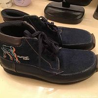 Side and top view of pair of vintage denim and leather Fubu boots featuring Fat Albert embroidery and Platinum Fubu branding.