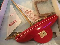 Photo of the vintage red and white Coca-Cola City of Lakes advertising boat model with sails.