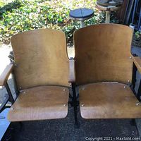 Front view of two connected wooden auditorium chairs on metal frame showing seats and backrests