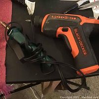 Photo showing the Black & Decker cordless drill with orange and black grip body and an attached tool for rotary function.