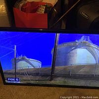 Samsung TV displaying clear image of industrial tanks from FOX 5 news channel, showing vivid blue sky and crisp image.